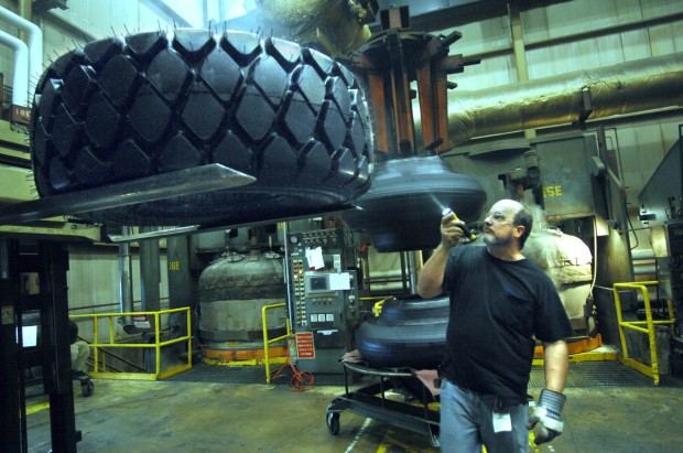 Оператор пресса на заводе Bridgestone Firestone в Нормале (США) с помощью фонаря производит осмотр еще дымящейся после пресса новой покрышки